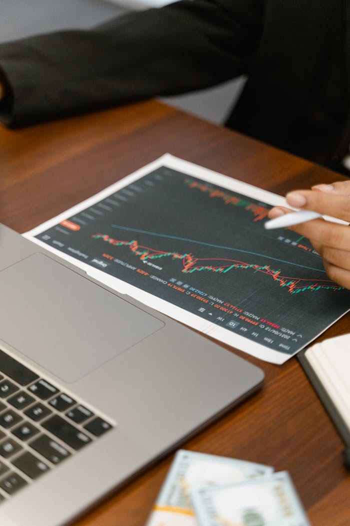creative-approach-img Close-up of business analysis with a laptop, chart, and currency on a wooden table.